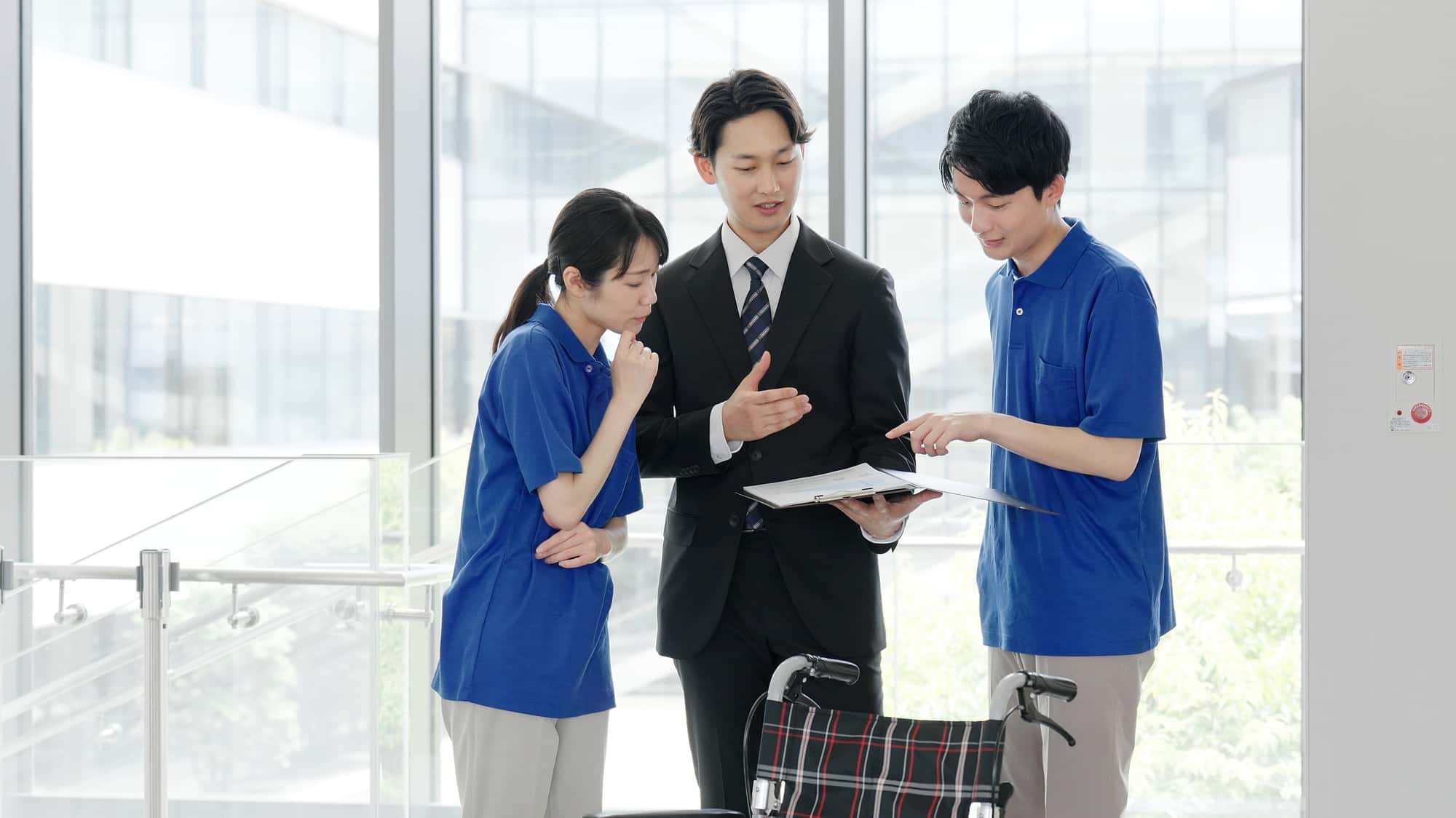 資料を片手に説明を行うビジネスパーソンと2人のスタッフ