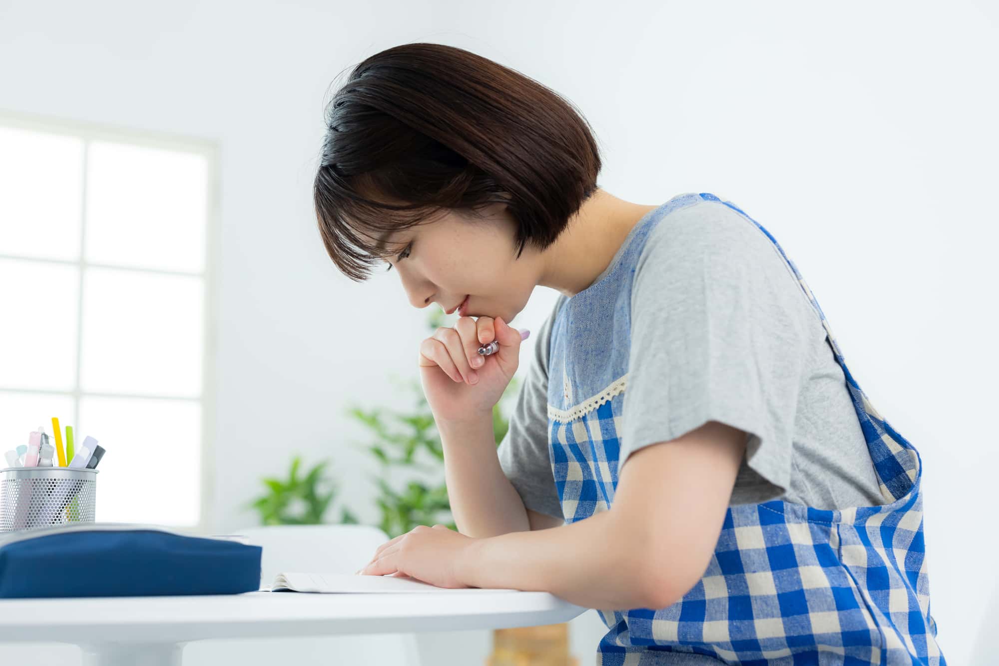 机の上の書類を熱心に見つめる女性