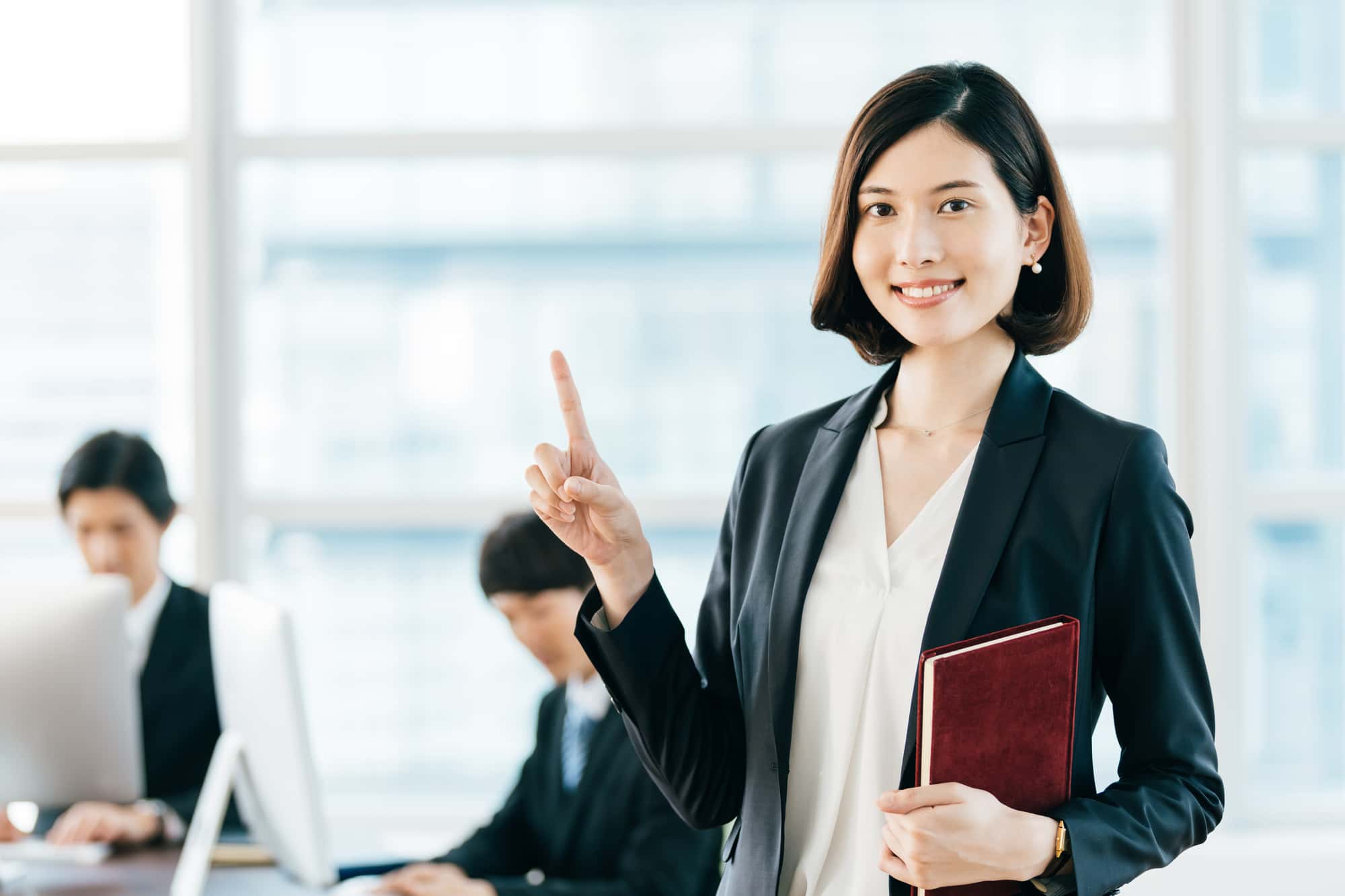 オフィスで人さし指を立てて、ポイントを表す女性