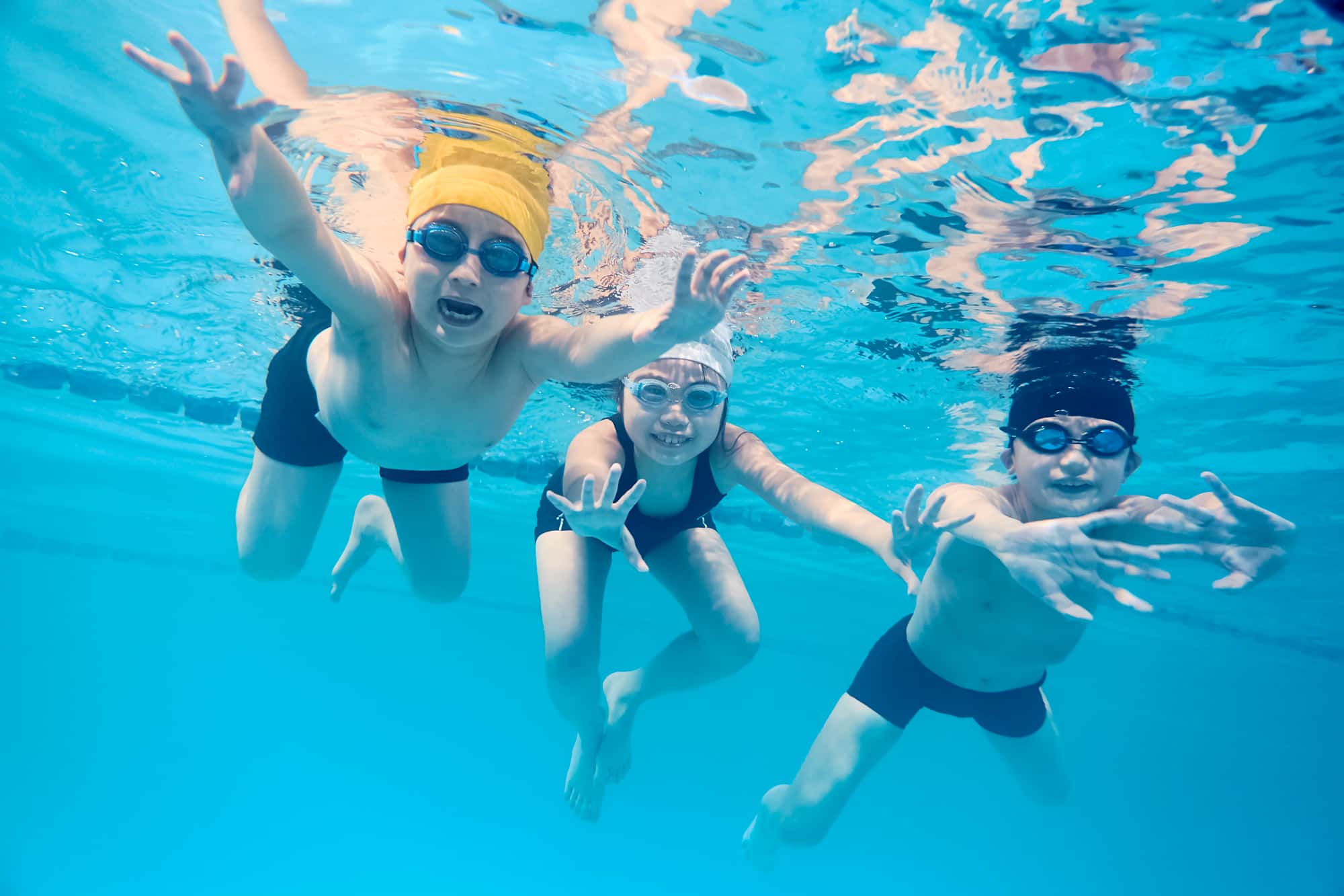 プールで泳ぐ3人の子ども