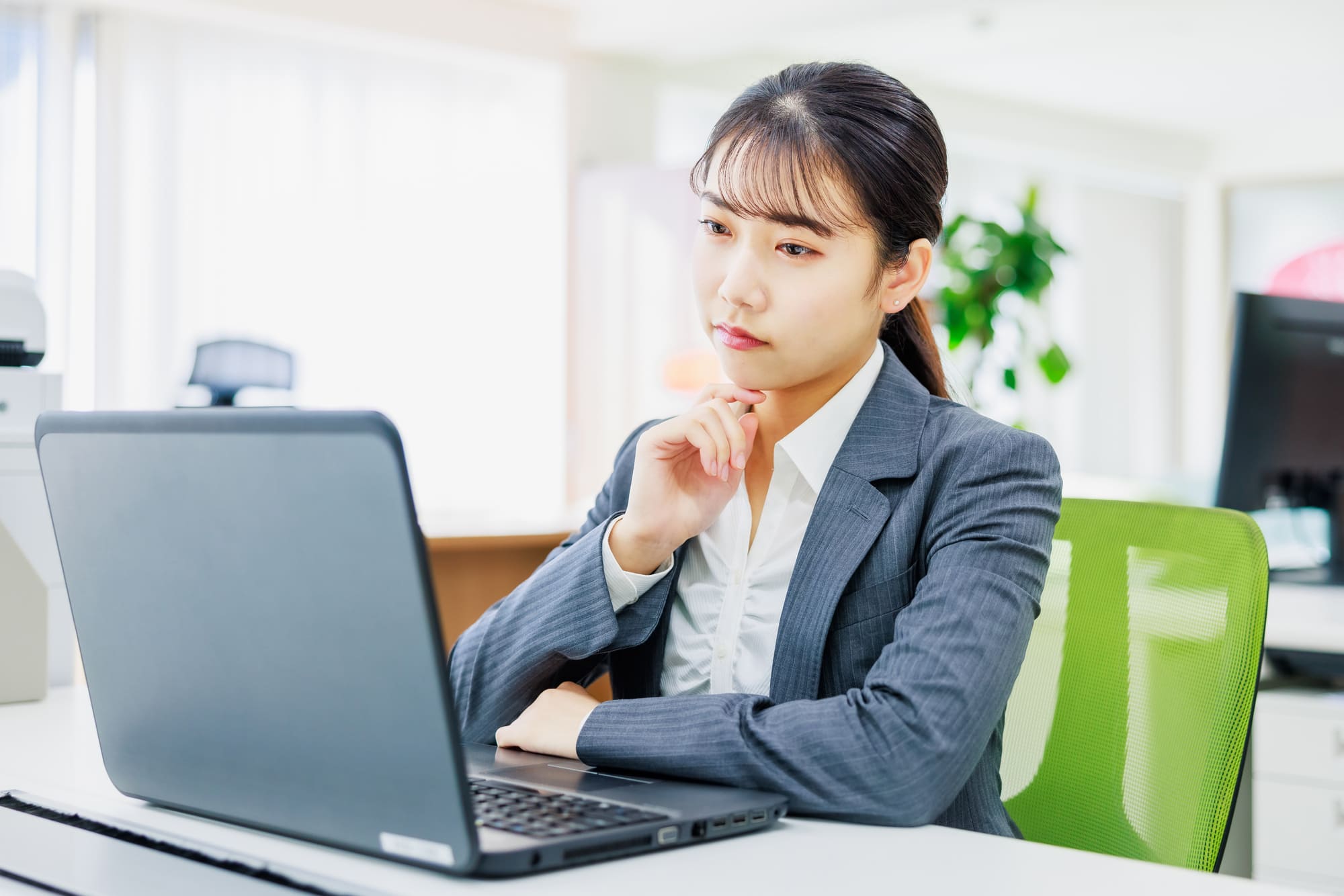 オフィスでパソコン画面を見つめて悩む女性