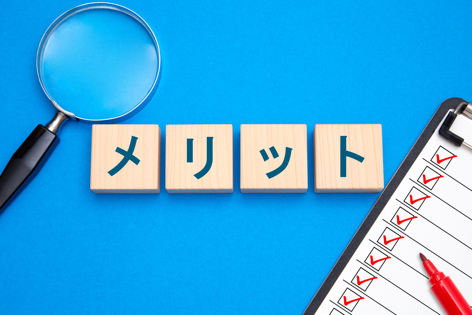 メリットと書かれた木のブロック、虫眼鏡、チェックリスト