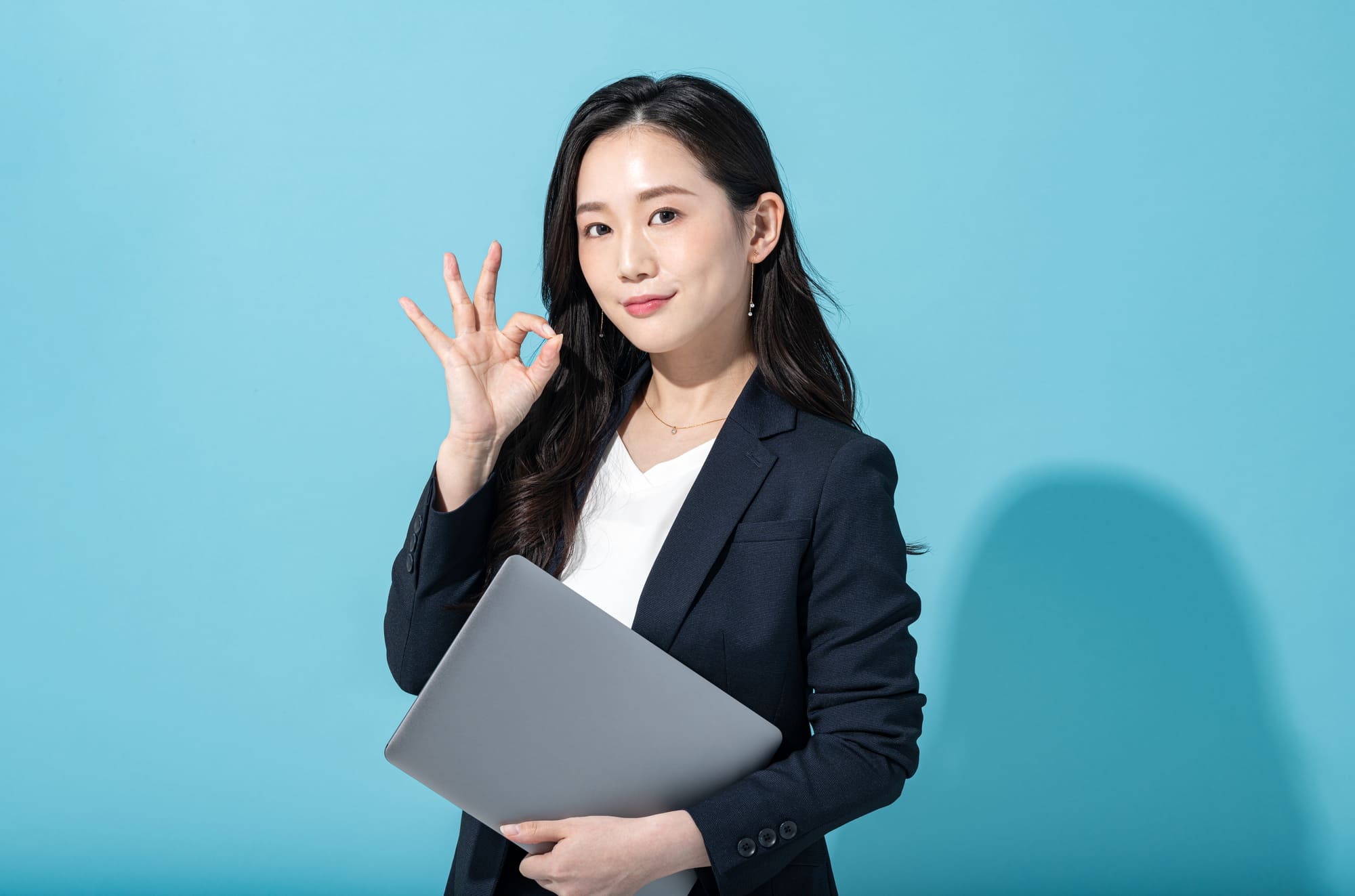 手でOKサインをするスーツ姿の女性