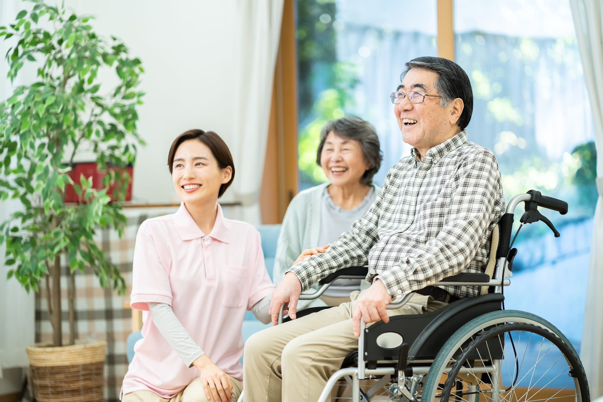 笑顔を浮かべる介護スタッフと車椅子に座っている男性、その家族
