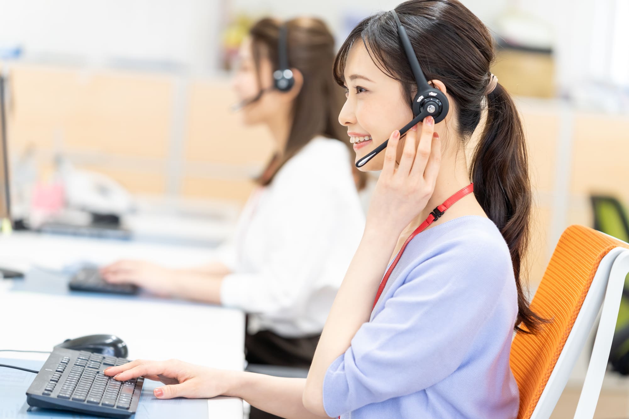 コールセンターで笑顔で働く女性