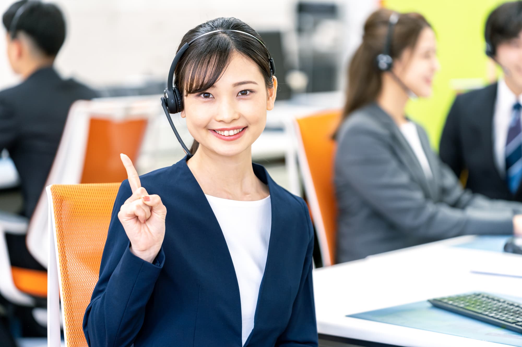 人さし指を立てて笑顔を浮かべるコールセンターのスタッフ