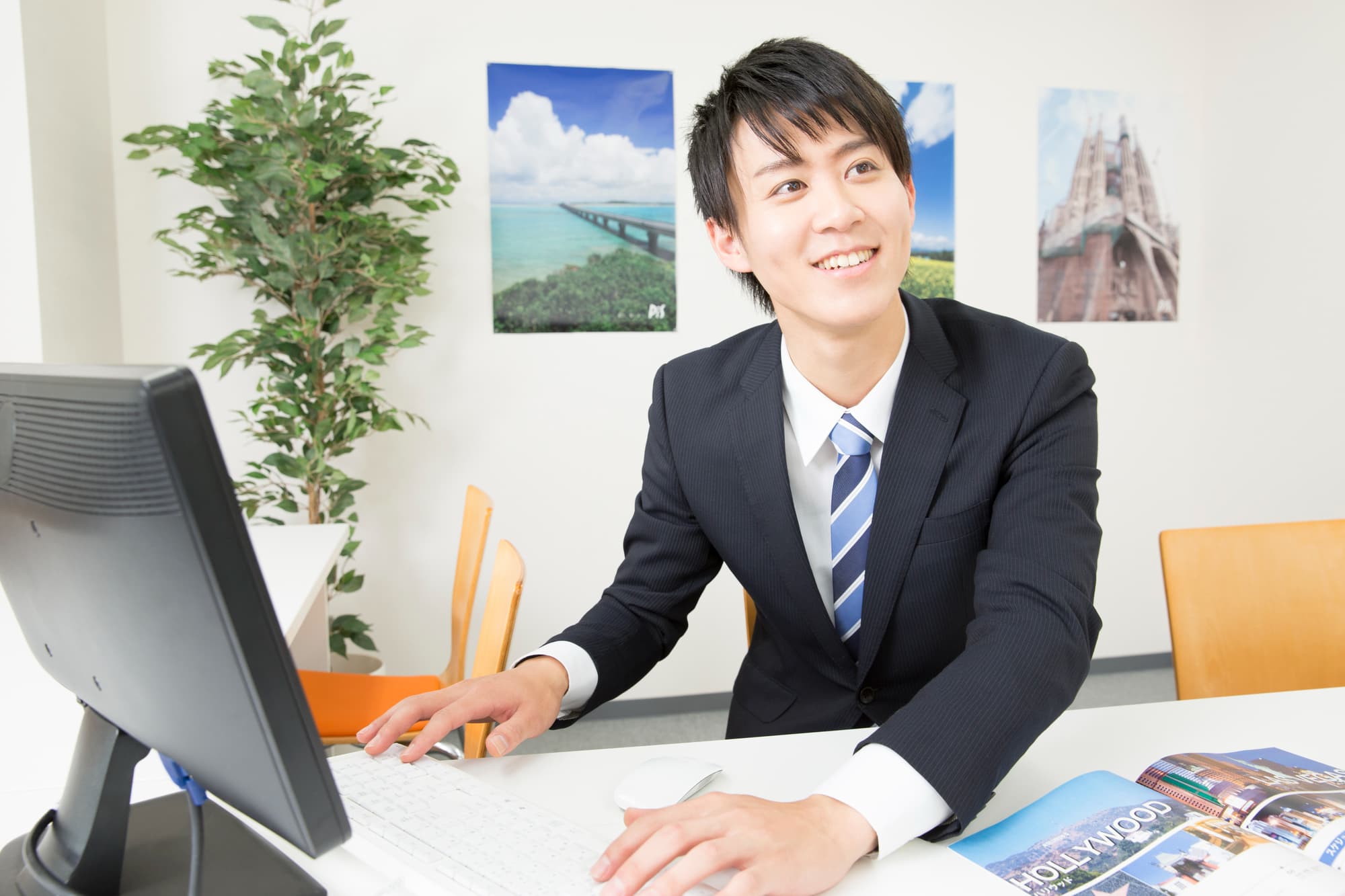 パソコンを操作しながら笑顔を浮かべる旅行会社のスタッフ