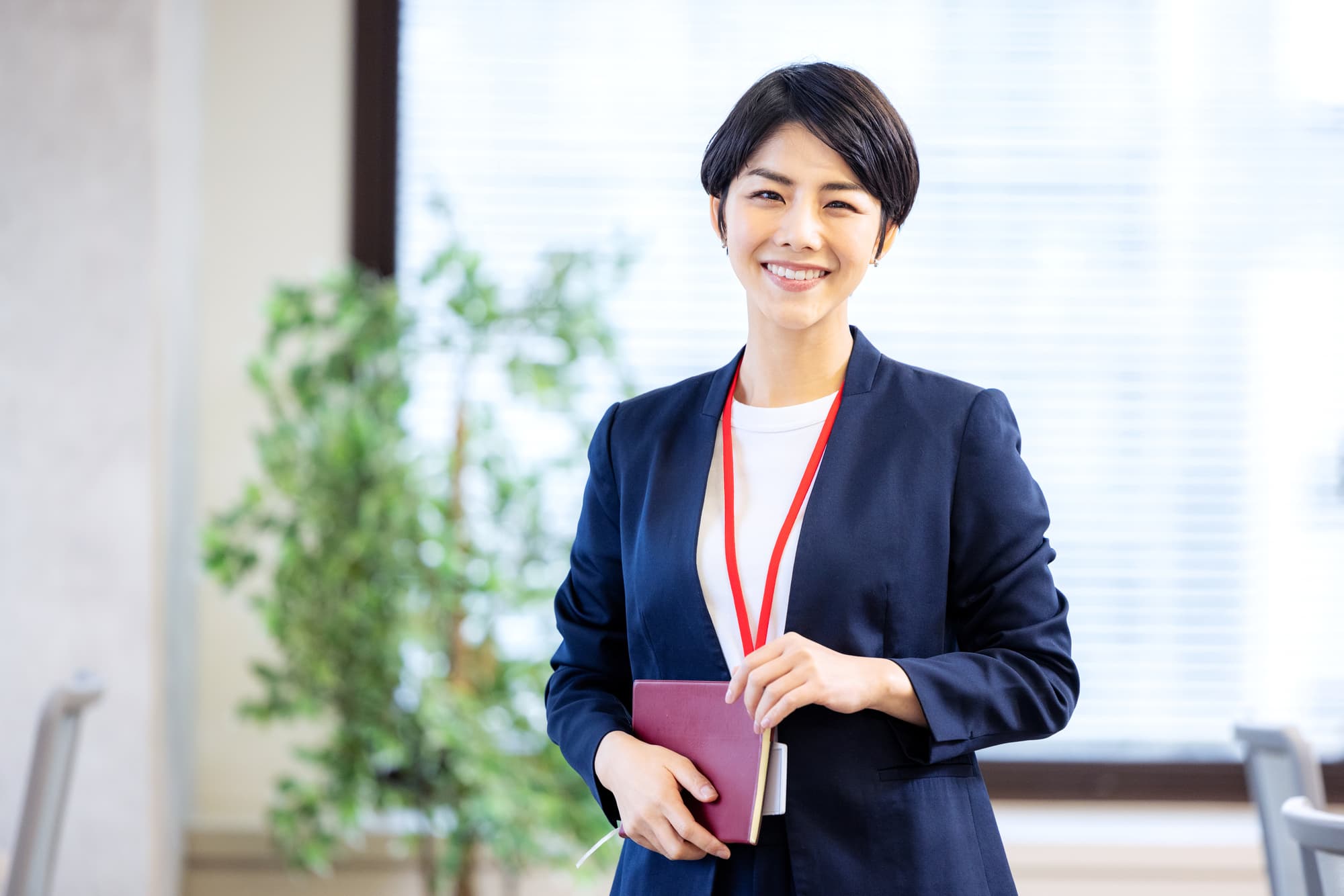 オフィスで手帳を持ち、笑顔を浮かべる女性