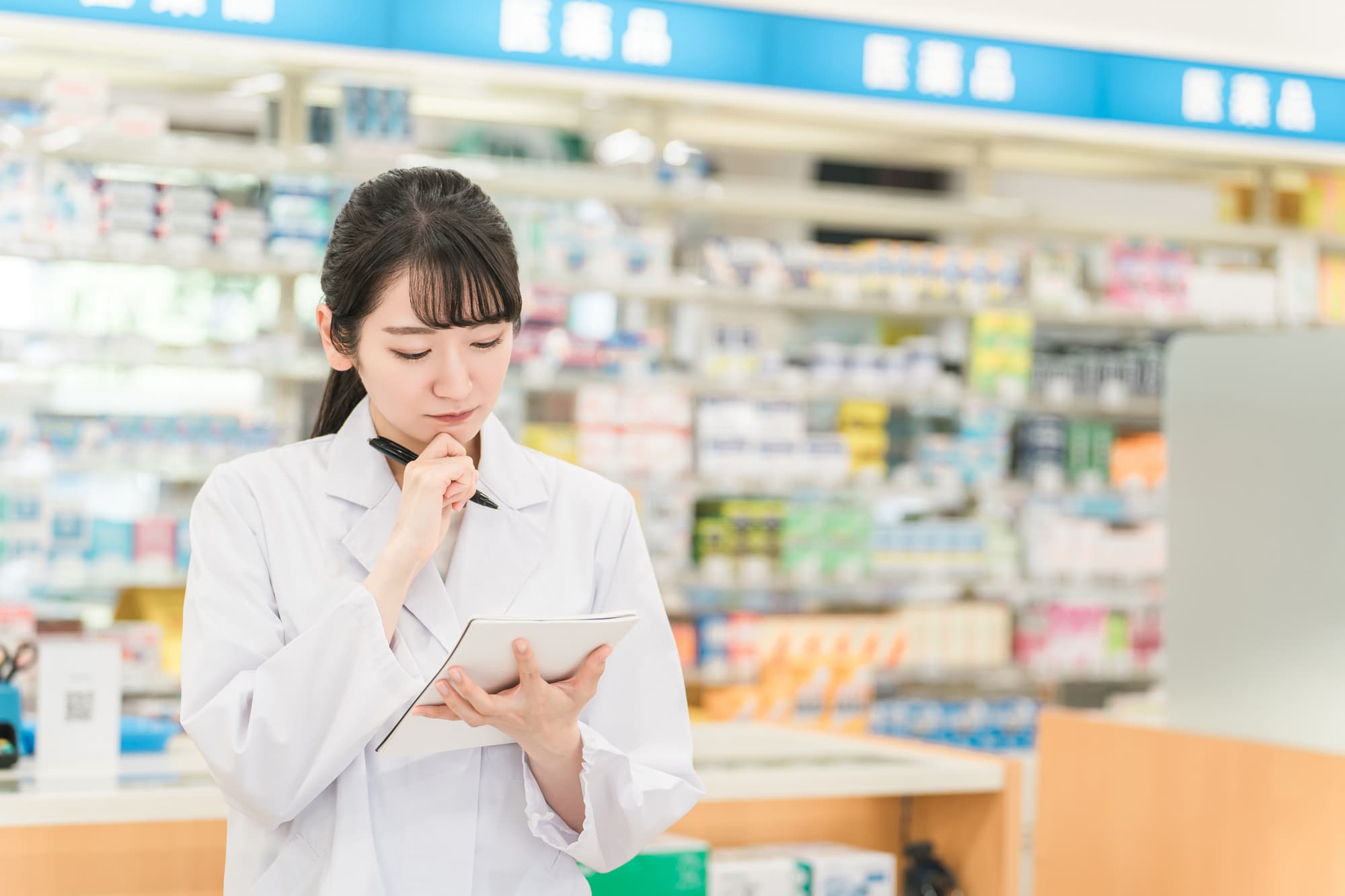 ノートを見ながら悩む薬剤師