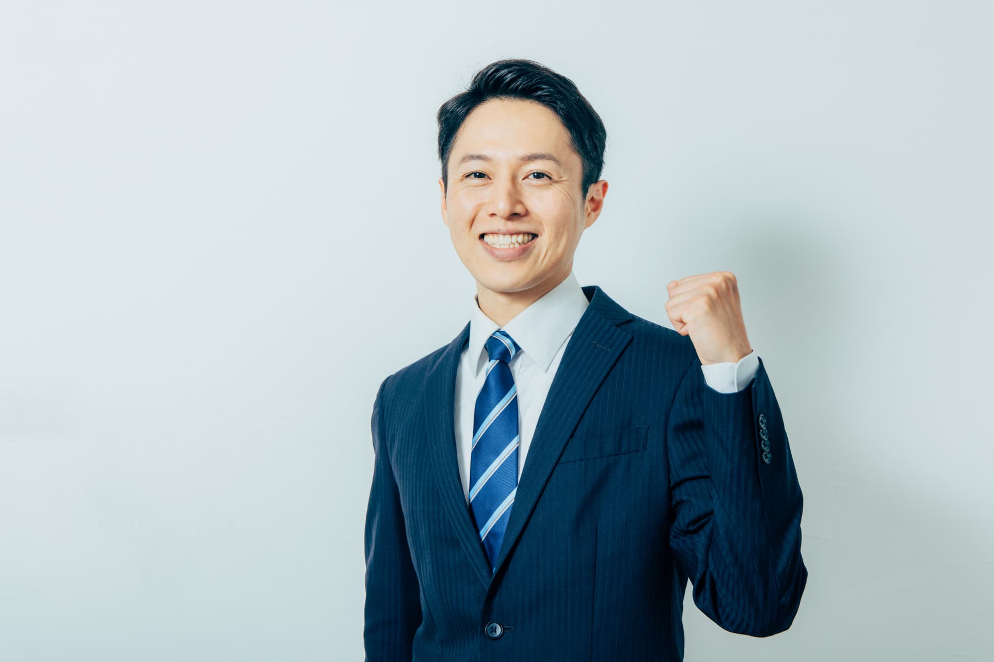 握りこぶしを作り笑顔を浮かべるビジネスパーソン
