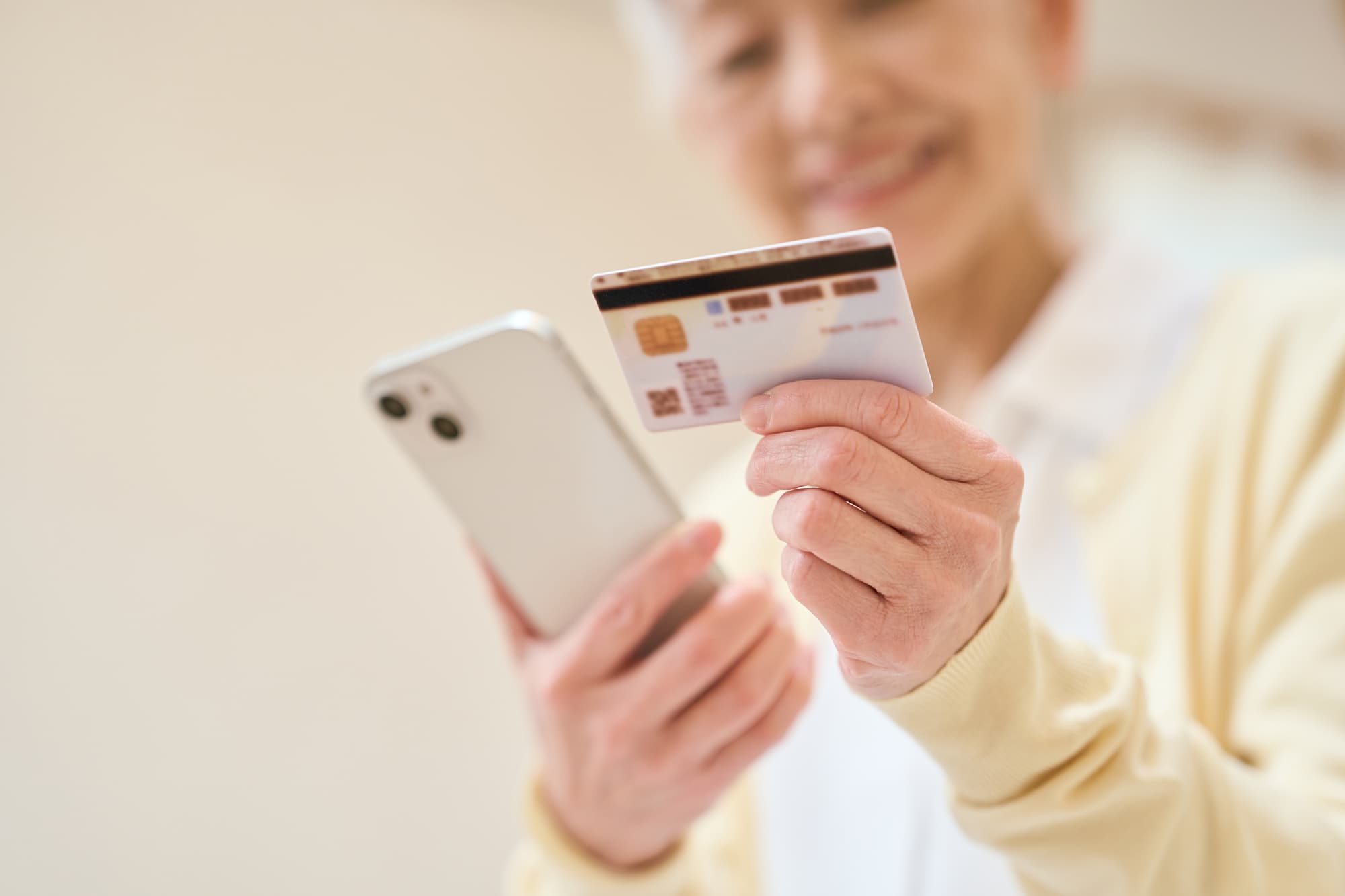 カードを見ながらスマホをチェックしている女性
