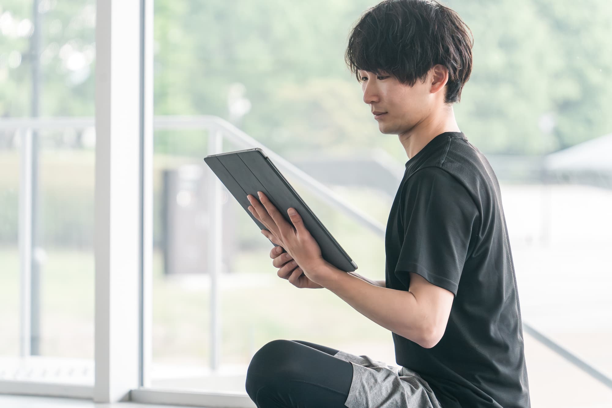 タブレットを真剣な表情で見つめるトレーナー