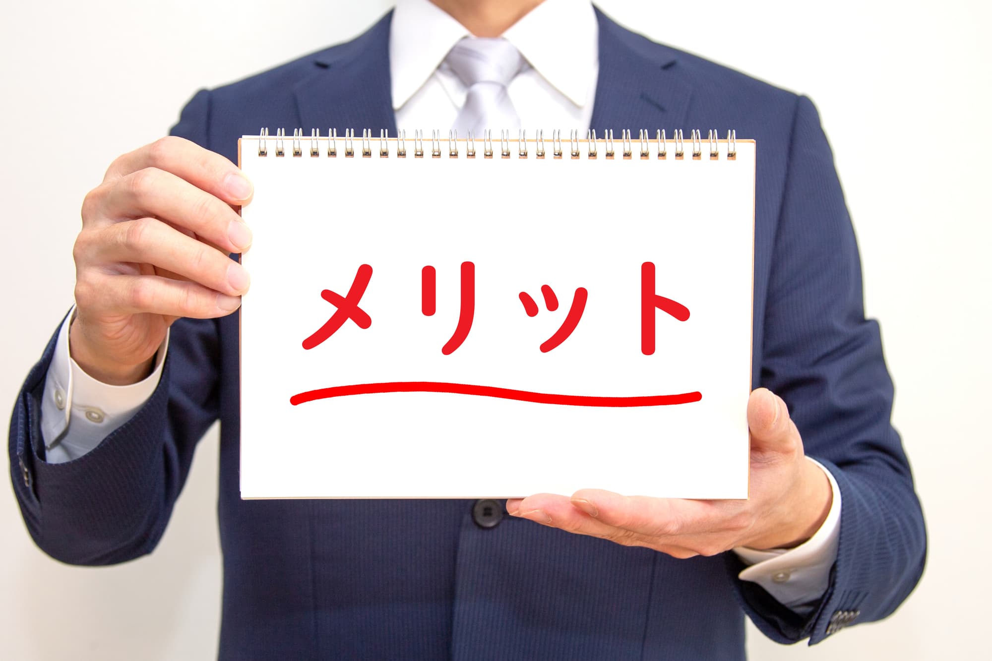 メリットと赤字で書かれた紙を持っている男性