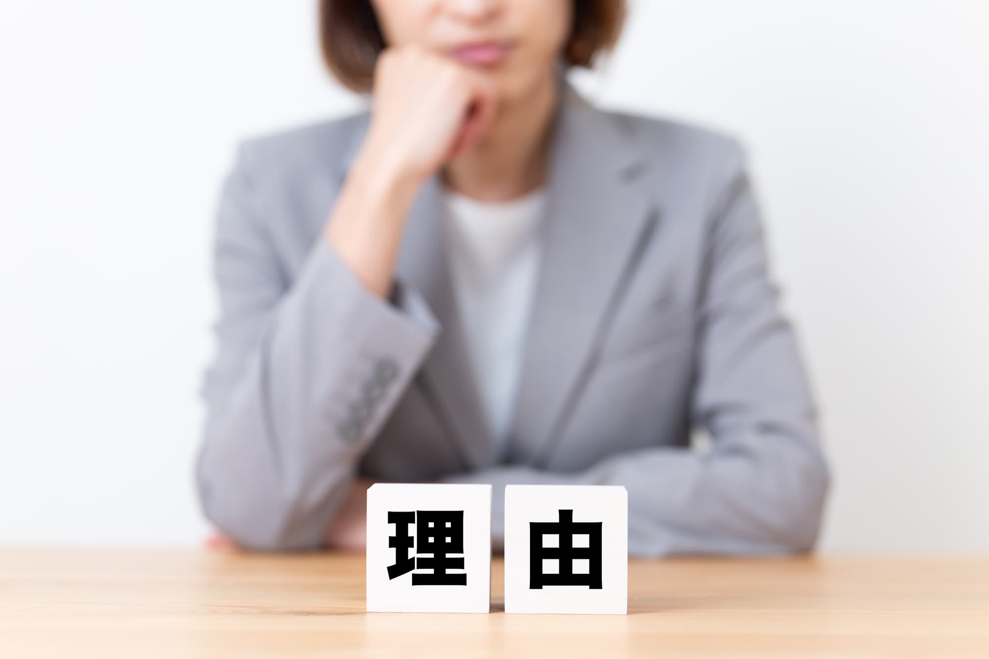 理由と書かれたブロックの後ろで悩んでいる人
