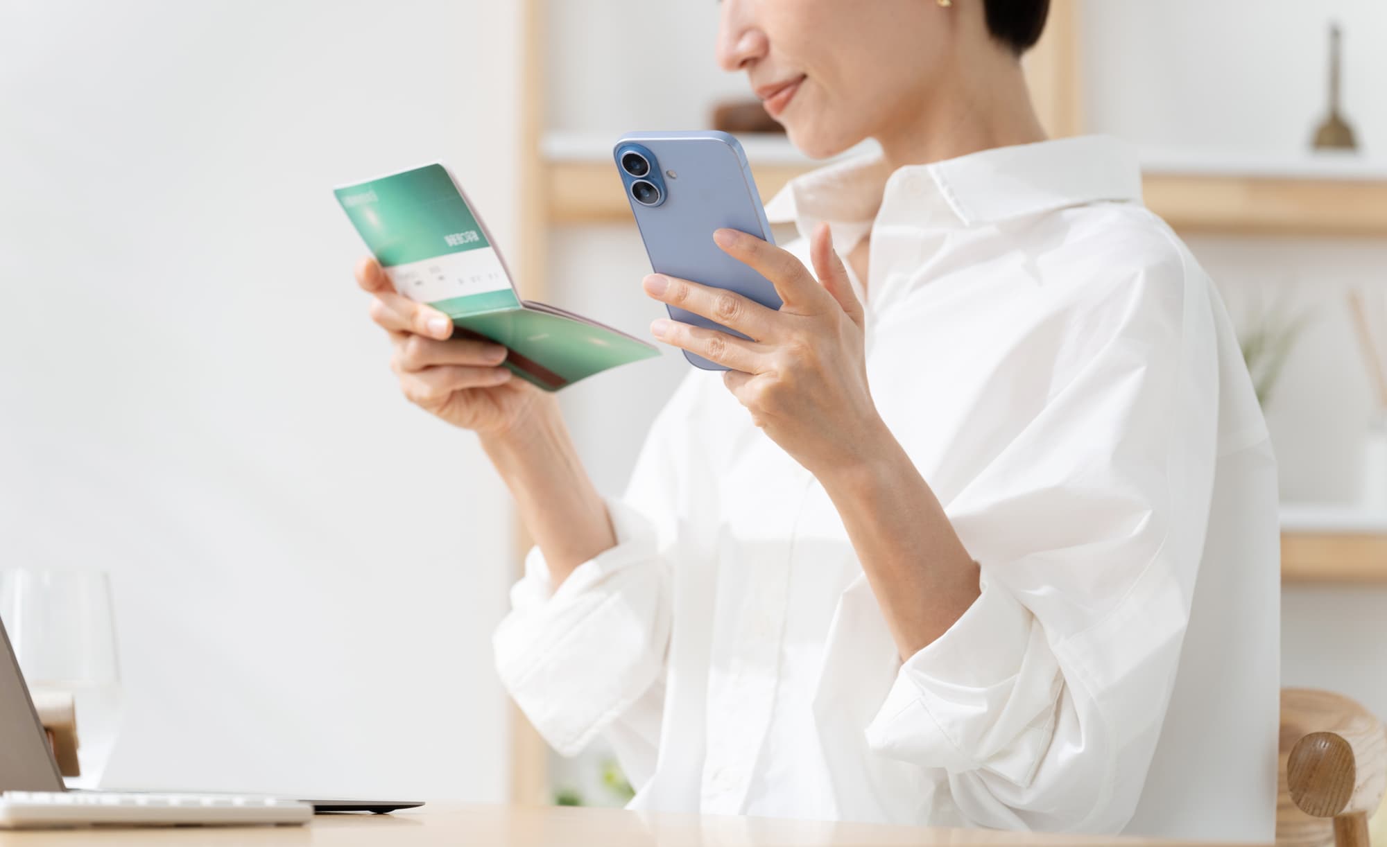 通帳を見ながらスマホを操作している人