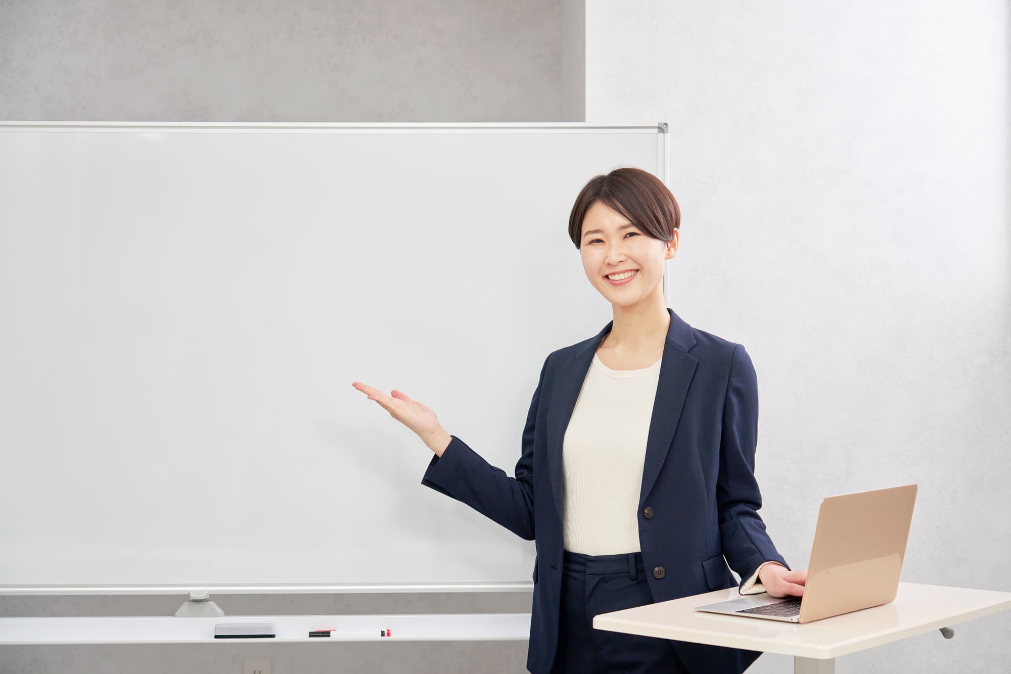ホワイトボードを手のひらで指すビジネスパーソン