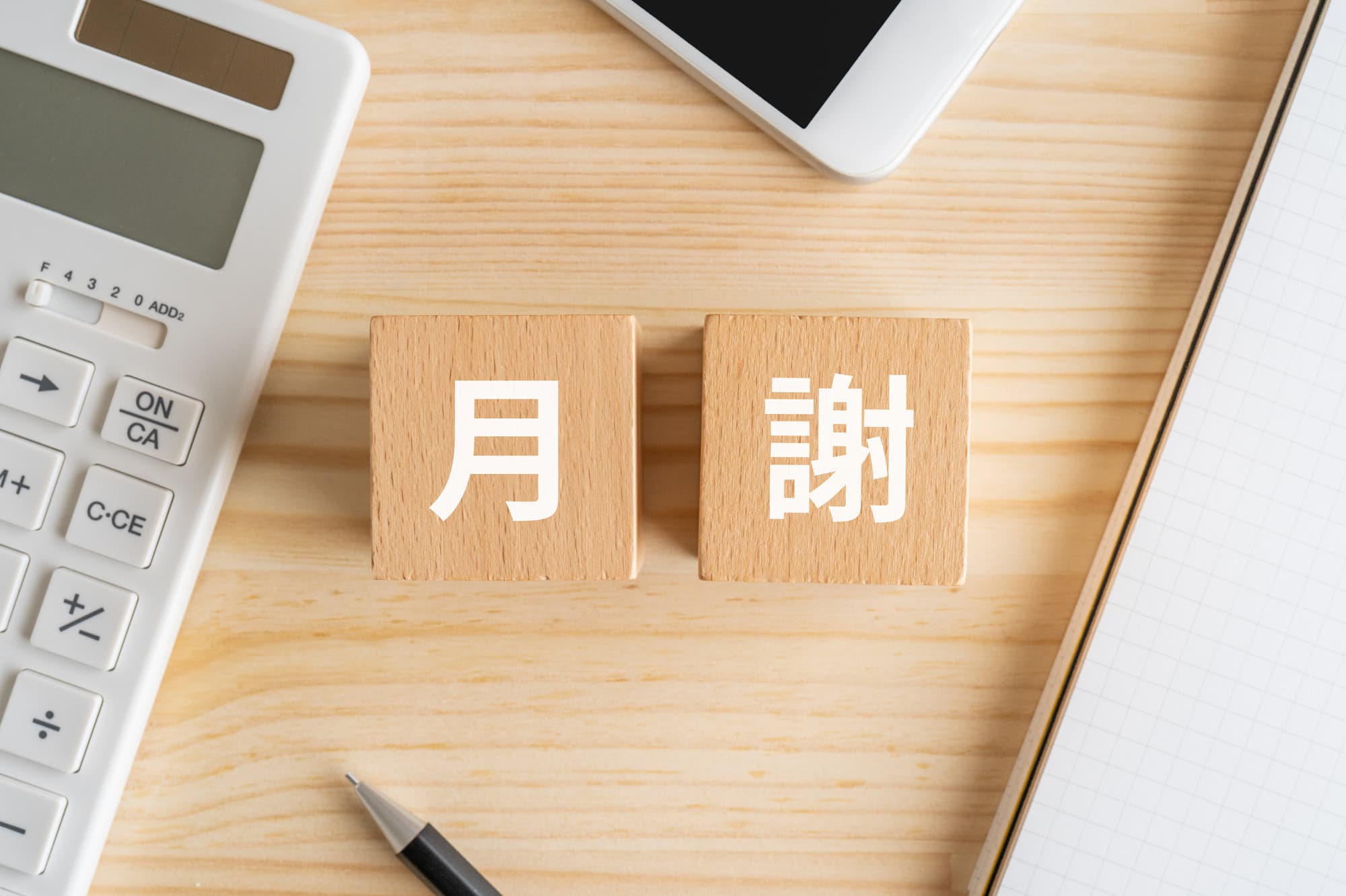 月謝と書かれたブロックと電卓、ペン